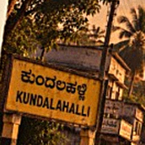 A yellow Kundalahalli signboard by the road